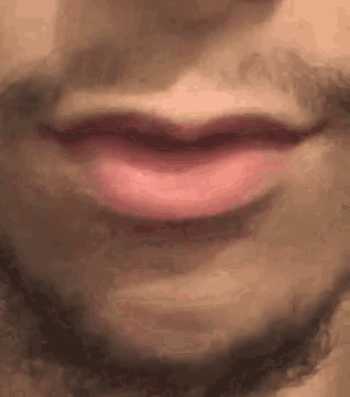 a close up of a man 's mouth with a beard and red lips .
