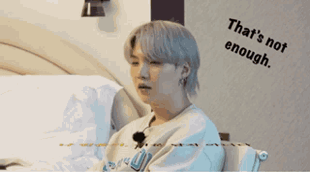 a person sitting on a bed with the words that 's not enough written on the wall behind them