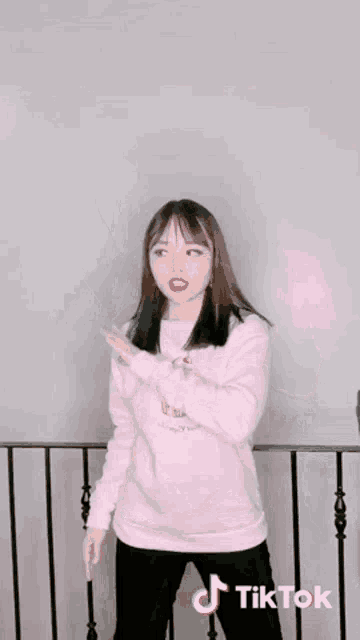 a woman wearing a pink sweater with a cupcake on it is dancing on a tiktok video