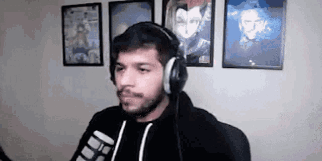 a man with a beard wearing headphones is standing in front of a microphone in a room .