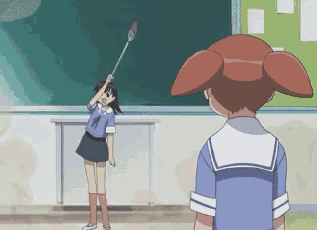 a girl is holding a stick in front of a blackboard while another girl stands behind her