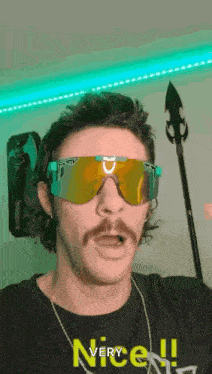 a man with a mustache is wearing sunglasses and holding a stick .