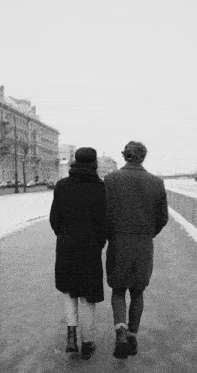 a black and white photo of a man and woman walking down a sidewalk