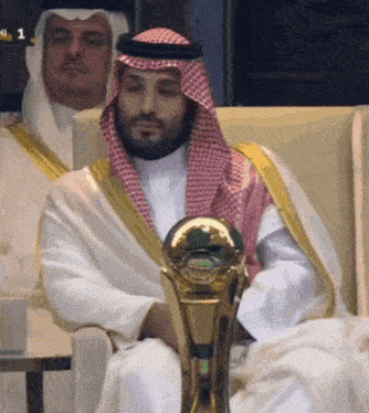 a man in a white robe is holding a trophy with the number 1 on it