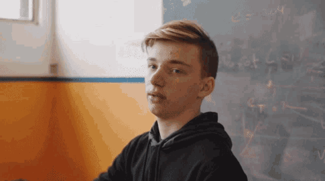 a young man sitting in front of a blackboard with the equation e = 304 written on it