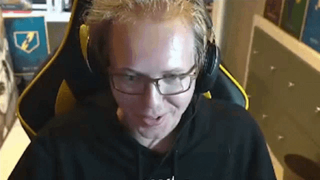 a man wearing glasses and headphones is sitting in a chair and making a funny face .