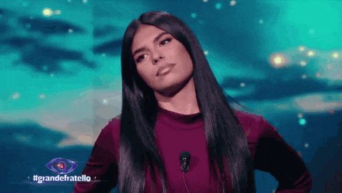 a woman stands in front of a microphone in front of a blue background that says grandefratello on it