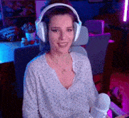 a woman wearing headphones and a necklace is sitting in a chair holding a microphone .