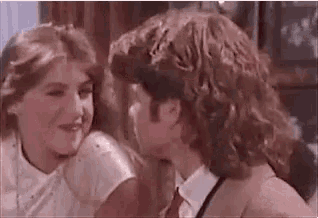 a man and a woman are sitting next to each other and kissing .
