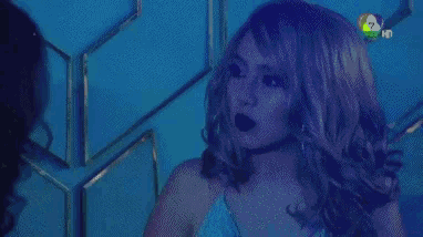 a woman in a green wig is standing in front of a blue wall .