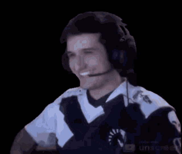 a man wearing headphones and a microphone is smiling and waving his hand .
