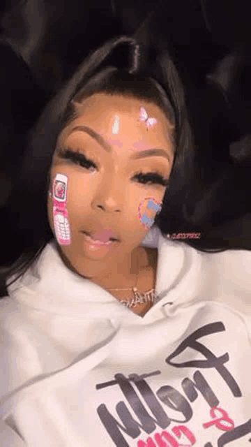 a girl with a bandage on her face is wearing a white hoodie and a necklace .