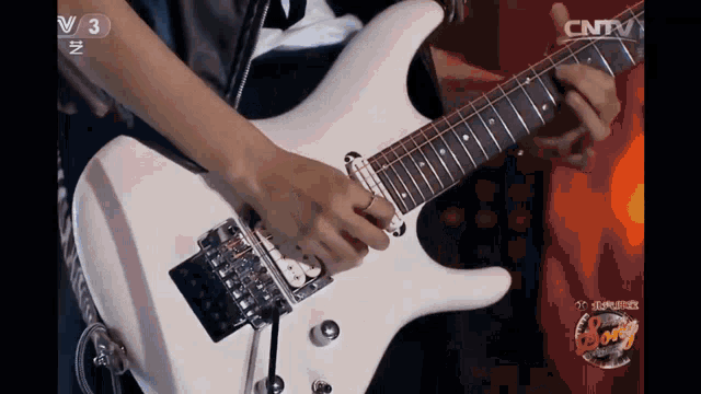 a person playing a white guitar with cntv written on the bottom