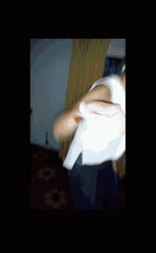 a woman in a white top is dancing in front of a window