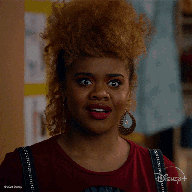 a woman with a surprised look on her face is wearing a disney+ shirt