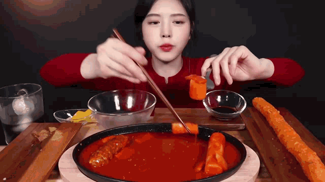 a woman is eating a meal with chopsticks and a bowl of sauce