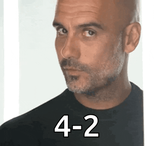 a bald man with a beard is wearing a black shirt and the number 4-2 is on the bottom .