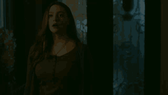 a woman is standing in a dark room with her eyes closed .