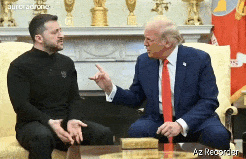 a man in a suit and tie is sitting next to a man in a black sweater