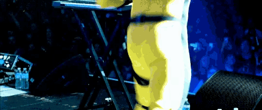 a person in a yellow suit is playing a keyboard on stage