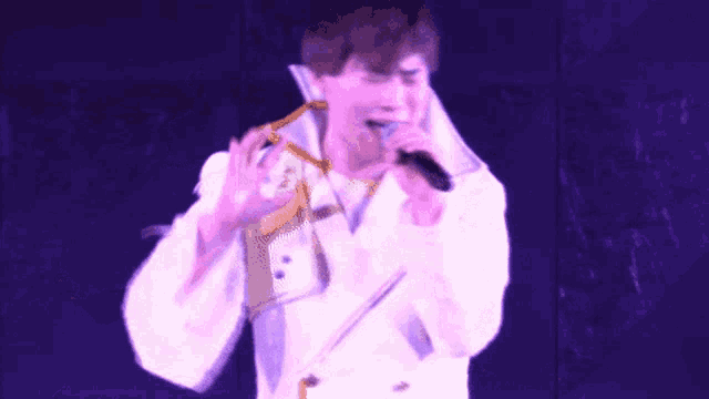 a man singing into a microphone with his hand up
