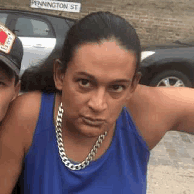 a woman wearing a blue tank top and a silver chain around her neck is standing next to a man .