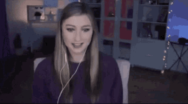 a woman wearing headphones is sitting on a couch in front of a computer screen .