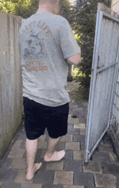 a man wearing a shirt that says " get life " is walking barefoot