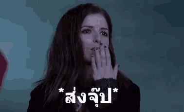 a woman with long red hair is covering her mouth with her hand in a dark room .