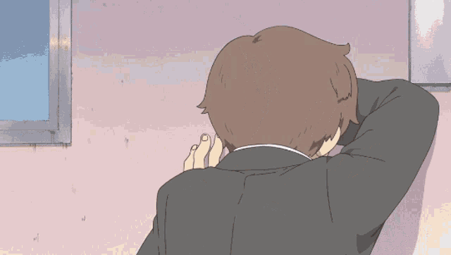 a man in a suit looks out a window with his hands behind his head