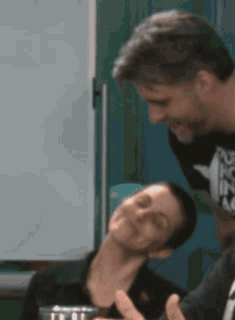 a man is putting his hand on a woman 's neck while another man looks on .