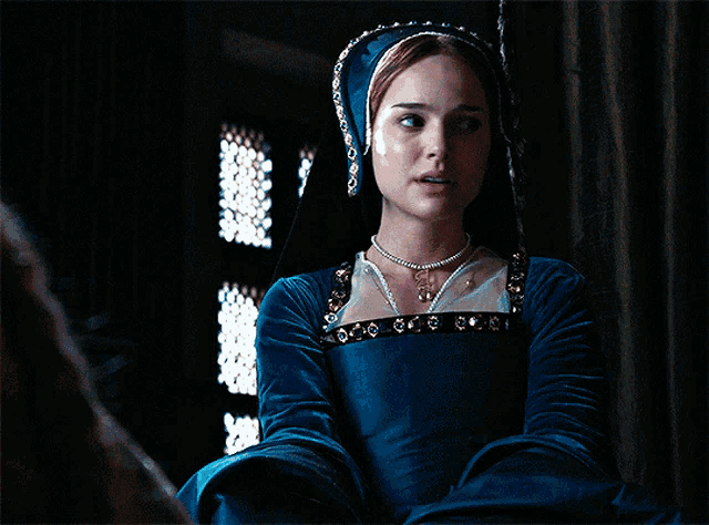 a woman in a blue dress has a necklace on