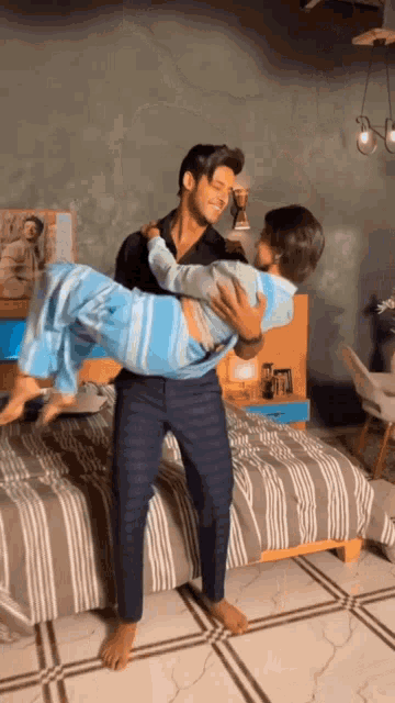 a man is carrying a woman in his arms in front of a bed