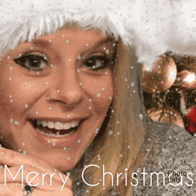a woman wearing a santa hat is smiling with the words merry christmas behind her
