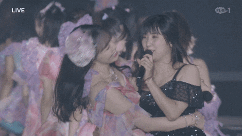 a woman holding a microphone in front of another woman with the word live on the bottom