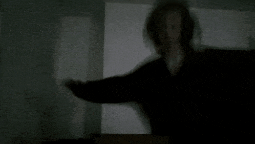 a shadow of a person holding a piece of paper in a dark room