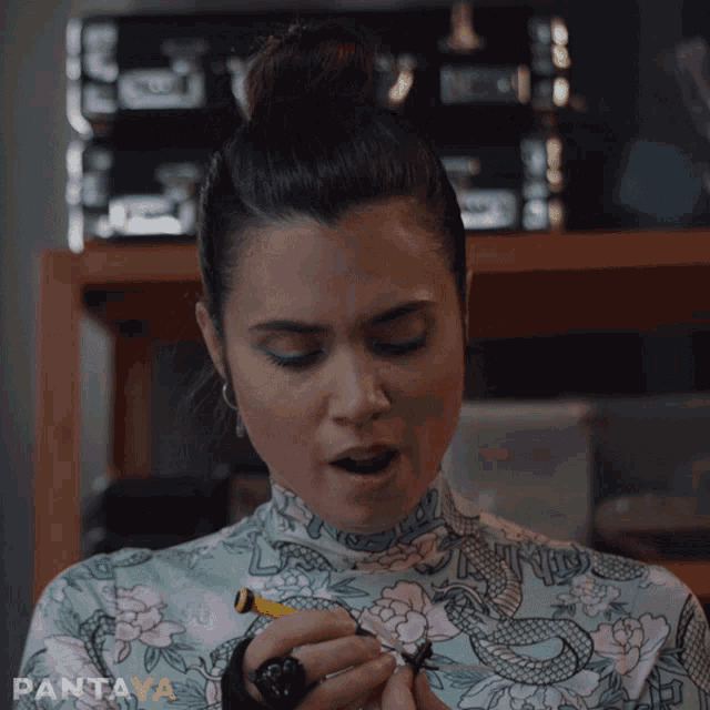 a woman in a floral top is smoking a cigarette with pantaya written in the corner