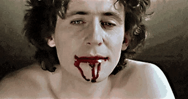 a shirtless man with blood dripping from his mouth and nose