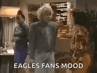 a man and two women are standing in a living room with the words `` eagles fans mood '' written above them .
