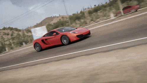 a red sports car is driving on a road