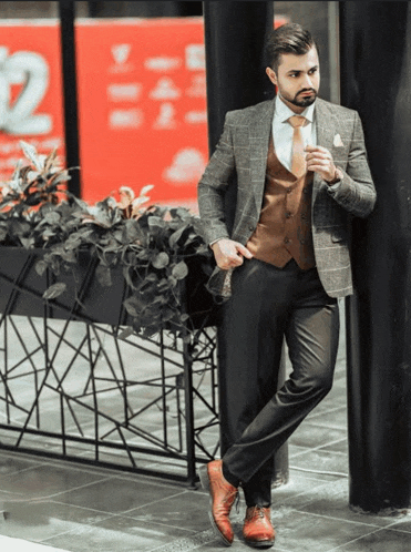 a man in a suit and tie is leaning against a wall