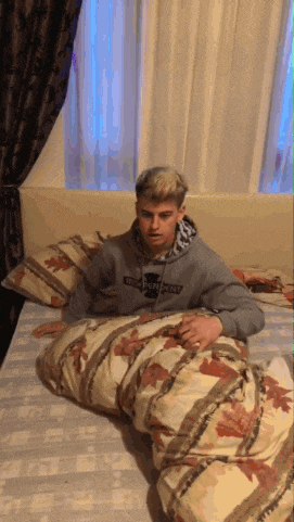 a man wearing a hoodie that says independent on it is laying on a bed