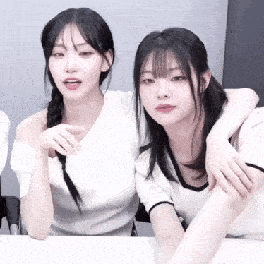 a couple of girls sitting next to each other with their arms around each other