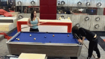 two women are playing pool and one is holding a cue