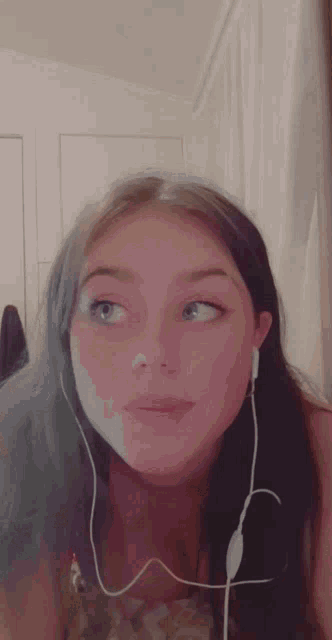 a girl wearing headphones looks at the camera while making a funny face .