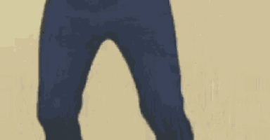 a close up of a person 's legs in blue jeans standing on a sandy surface .