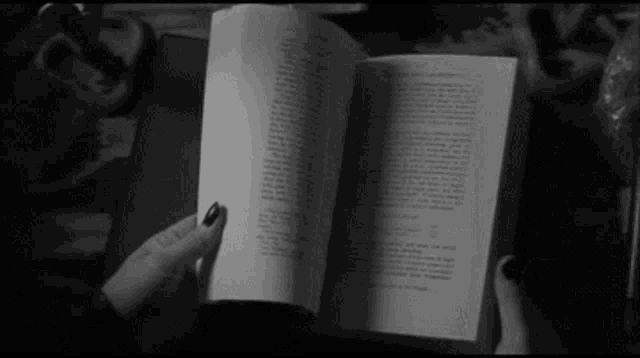 a person with black nails is reading a book