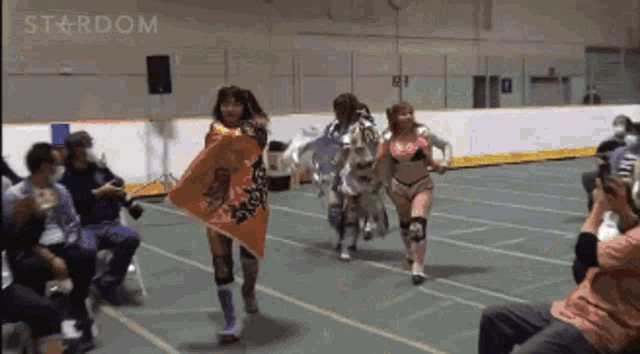 a group of women are running on a track with the word stardom on the bottom right