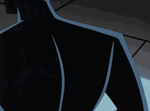 a silhouette of batman 's head is against a dark wall