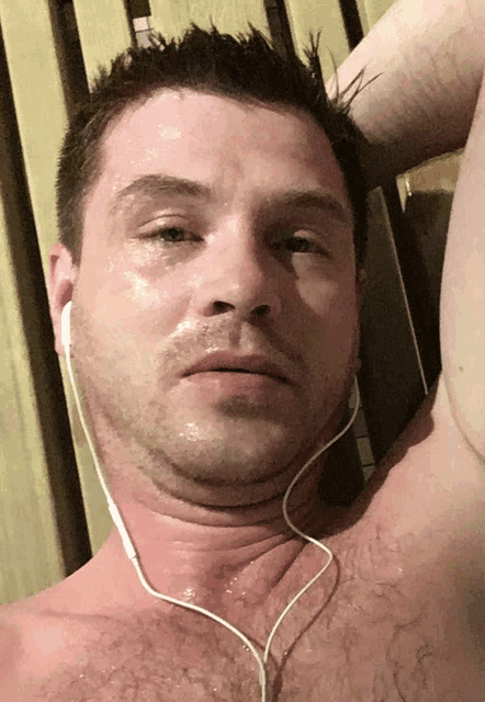a shirtless man wearing ear buds and sweating